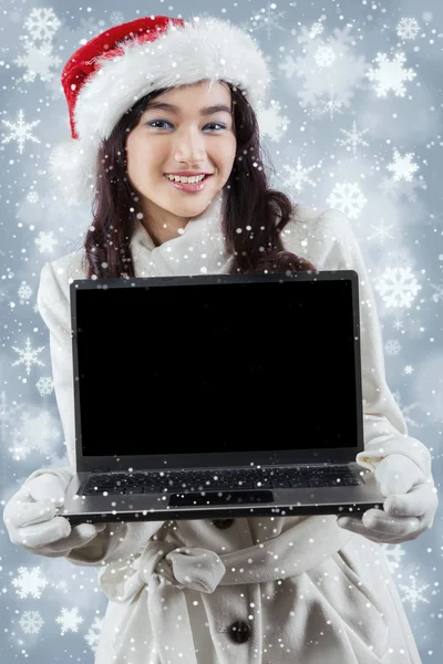 Girl in winter clothes showing laptop screen — Stock Photo, Image