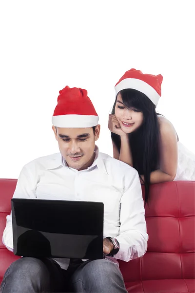 圣诞老人的帽子的女人看到她男朋友跟笔记本电脑 — 图库照片