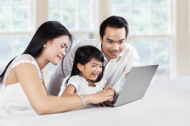 Parents teach their daughter to use laptop clipart