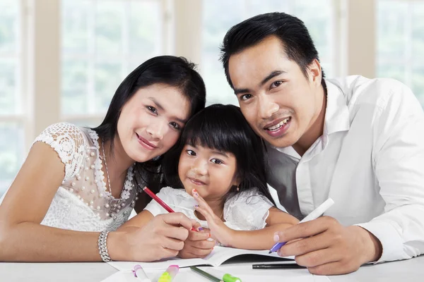 Girl doing homework with her parents — Stock Photo, Image