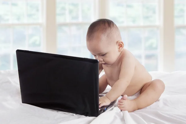 Baby with laptop on bedroom — Stock Photo, Image