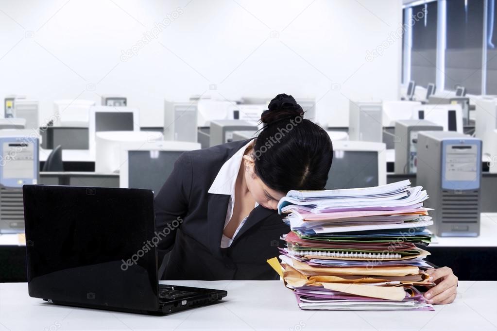 Exhausted worker napping over documents