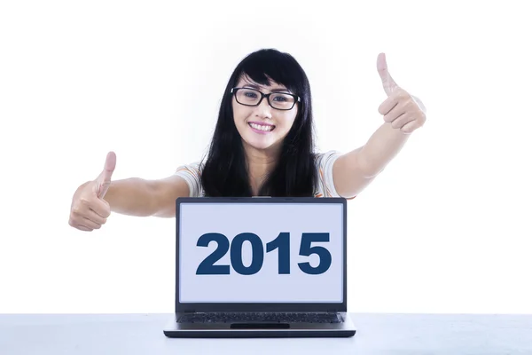 Flicka med tummen upp och nummer 2015 på laptop — Stockfoto