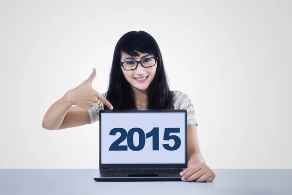 Pretty schoolgirl showing numbers 2015 on PC — Stock Photo, Image