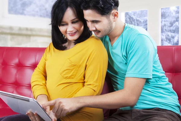 Привлекательная беременная пара играет на планшете — стоковое фото