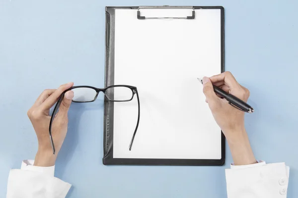 Médico mãos com óculos escrevendo no papel — Fotografia de Stock