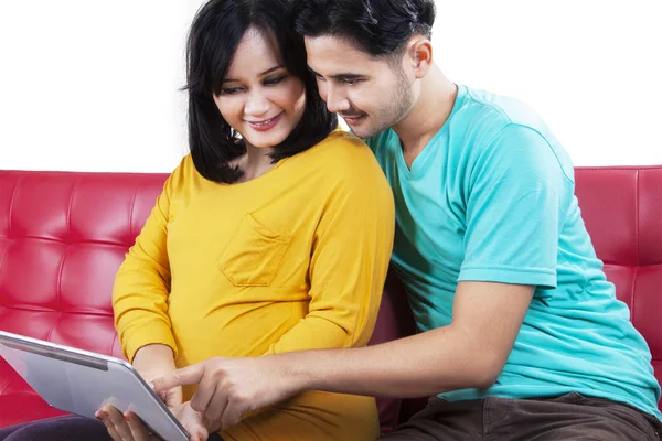 Mãe expectante com o marido usando tablet — Fotografia de Stock