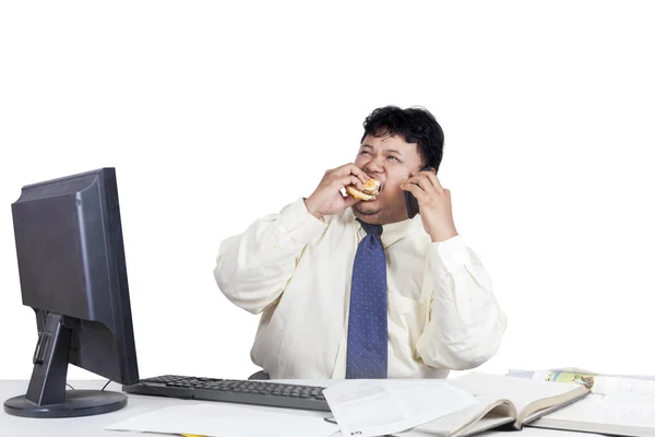 Empresario comiendo hamburguesa mientras trabaja — Foto de Stock