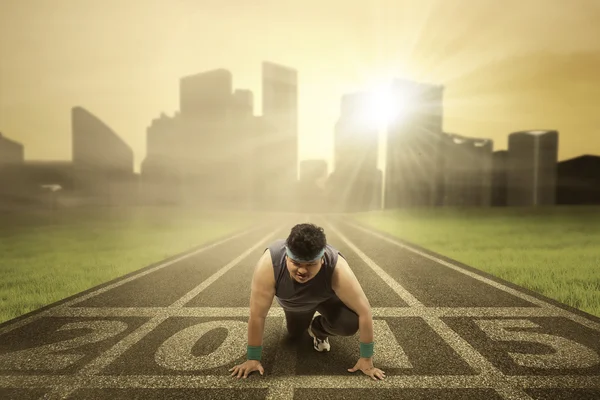 Obesity person kneeling on the track — Stock Photo, Image