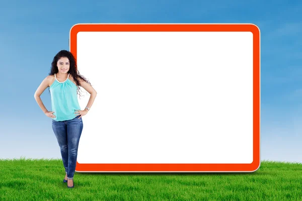 Casual woman standing next to billboard — Stock Photo, Image