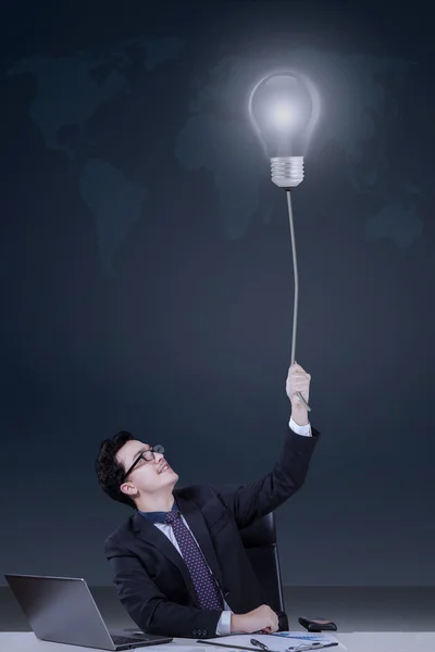 Young caucasian manager pulling lightbulb — Stock Photo, Image