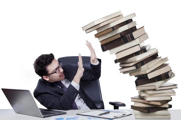 Male manager with falling books on desk Royalty Free Stock Images