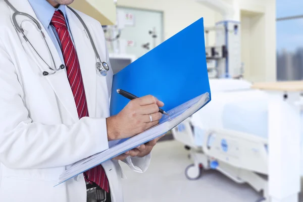 Doctor escribiendo en una carpeta — Foto de Stock