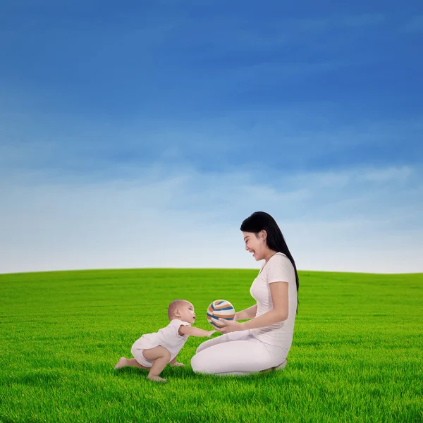 Moeder spelen met haar baby in voorjaar groen veld — Stockfoto