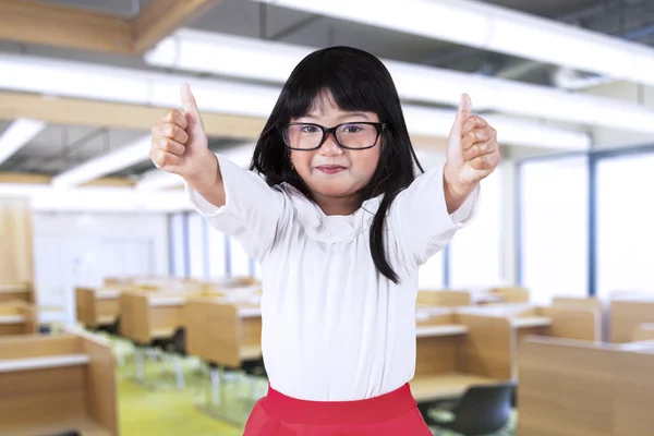 Colegiala mostrar pulgares hacia arriba en clase — Foto de Stock