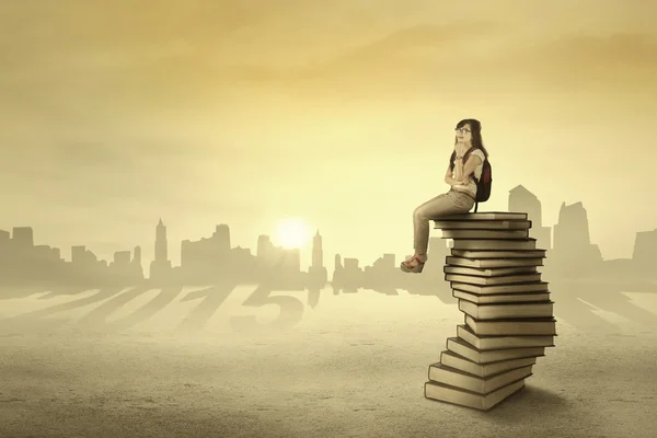 Student sitting and dreaming above books — Stock Photo, Image