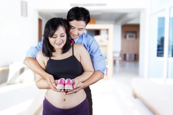 Padres jóvenes sosteniendo zapatos de bebé — Foto de Stock