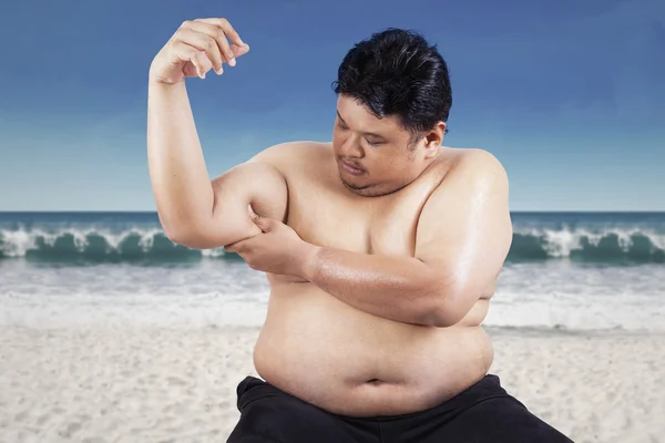 Tlustý muž drží své ochablé biceps — Stock fotografie