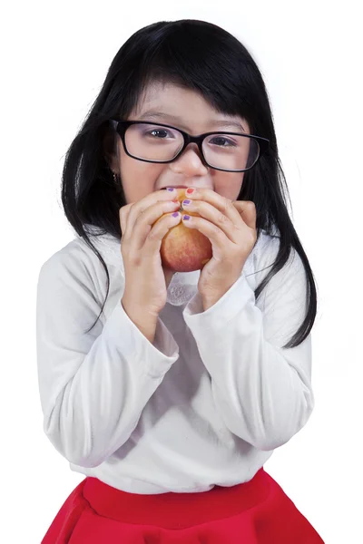 Little girl biting apple in studio — Stock Photo, Image