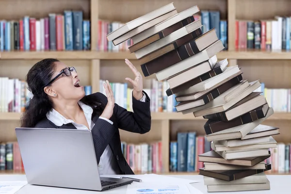 Беспокойный студент с осенними книгами в библиотеке — стоковое фото