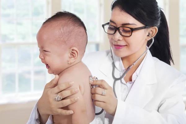 Jovem médico verificando pequeno bebê — Fotografia de Stock