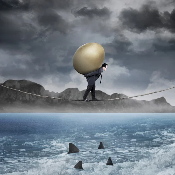 Empresário carrega ovo dourado acima do mar — Fotografia de Stock