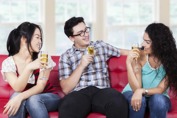 Friends drinking champagne on sofa — Stock Photo, Image