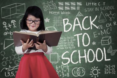 Yazı tahtası önünde bir kitap okumak kız