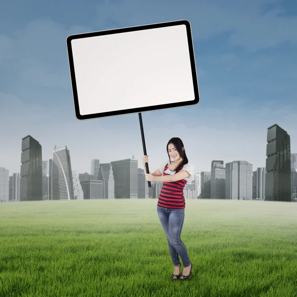 Menina segurando cartaz vazio no campo — Fotografia de Stock