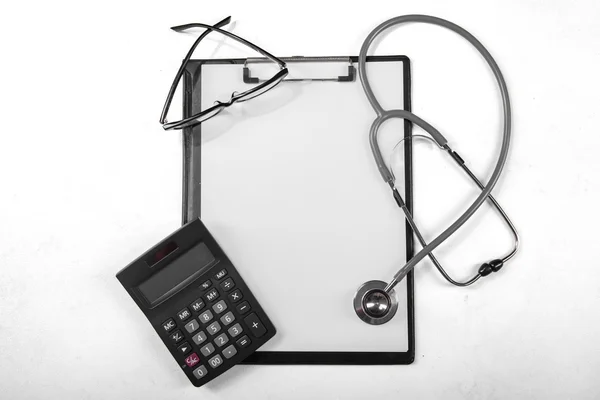 Presse-papiers avec calculatrice et stéthoscope — Photo