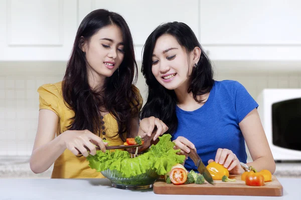 Gyönyörű lányok, főzés a konyhában saláta — Stock Fotó