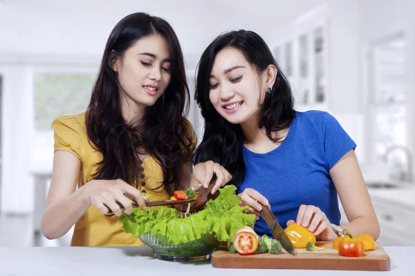 Meninas bonitas preparando salada de legumes — Fotografia de Stock