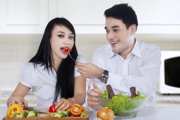 Beautiful couple cooking salad in kitchen — Stock Photo, Image