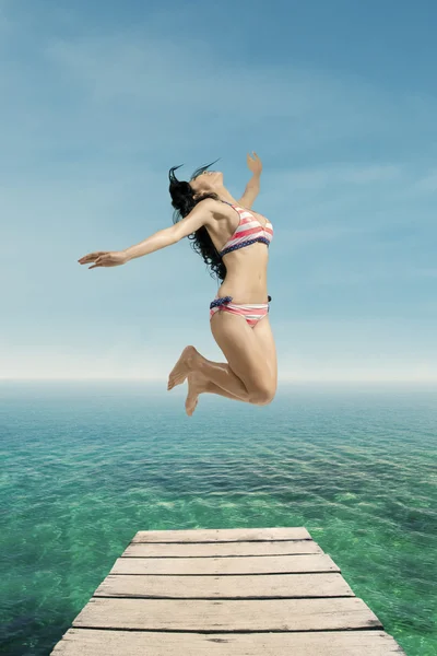 Excited woman in swimsuit jumps at pier — Stock Photo, Image