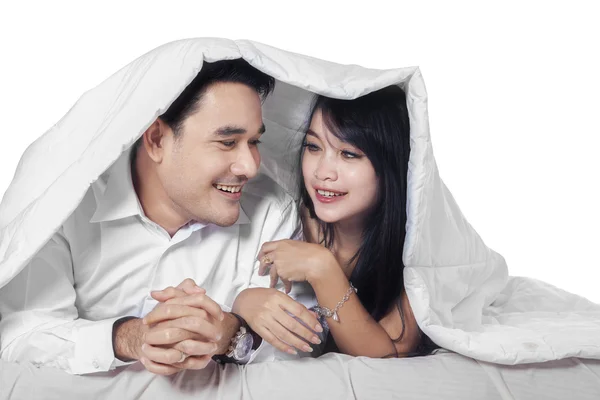 Spansktalande par på sängen under täcket — Stockfoto