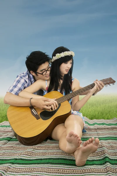 Casal atraente tocando guitarra no campo — Fotografia de Stock