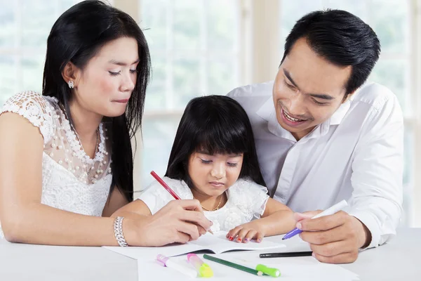 Kind studeren met ouders in huis — Stockfoto