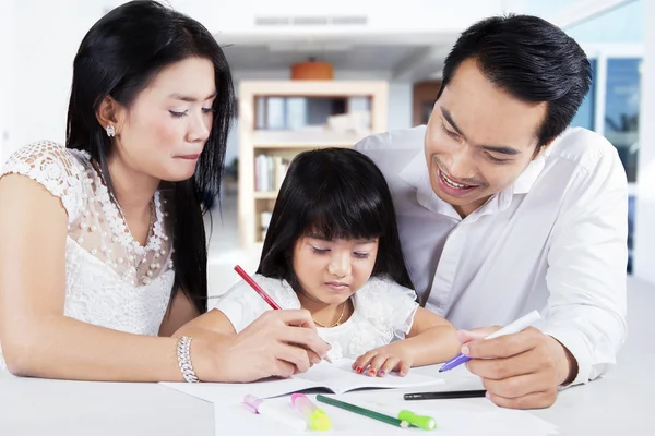 Flicka lära sig att skriva med föräldrar — Stockfoto