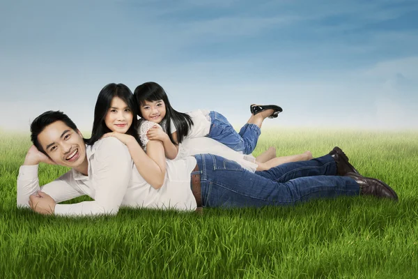 Радостная семья, лежащая на траве в парке — стоковое фото