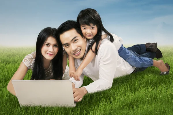 Familia moderna con portátil en la hierba —  Fotos de Stock