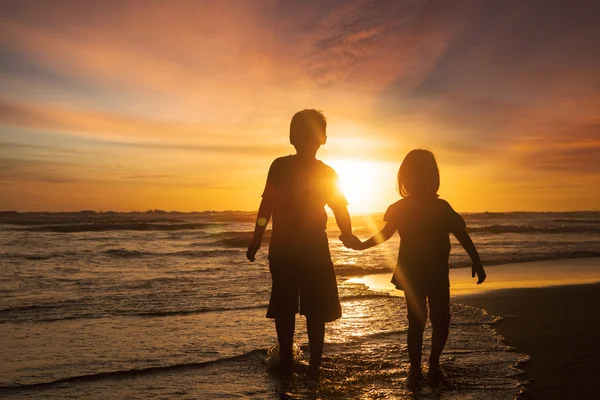 Dwoje dzieci trzymając się za ręce na plaży — Zdjęcie stockowe