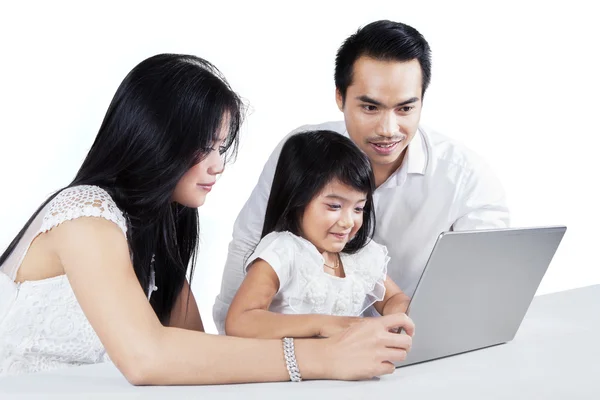 Twee ouders onderwijzen hun dochter met laptop — Stockfoto