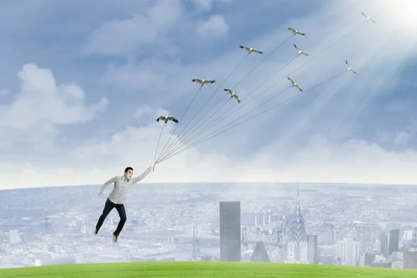 A young man is flying by holding birds — Stock Photo, Image