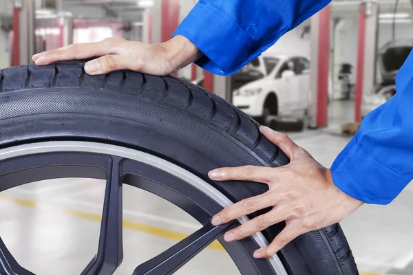 Mechanic hands pushing tire at workshop — Stock Photo, Image