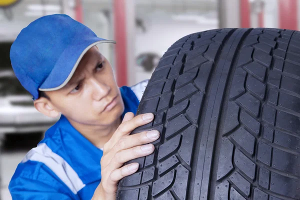 Mecânico verificando um pneu texturizado — Fotografia de Stock
