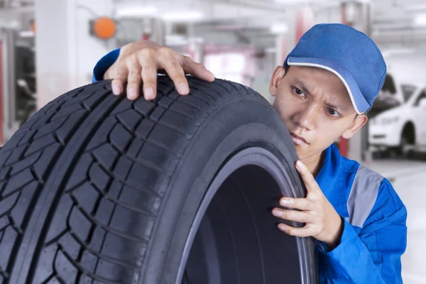 Técnico masculino controla um pneu — Fotografia de Stock