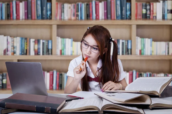 Teenage girl studying in the library — Stok fotoğraf