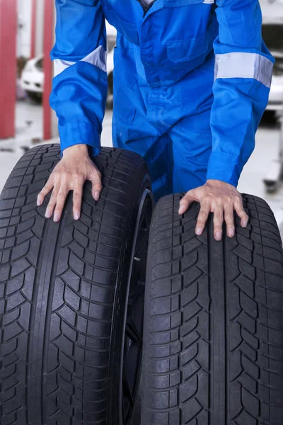 Two tires with mechanic in workshop — Stock Photo, Image