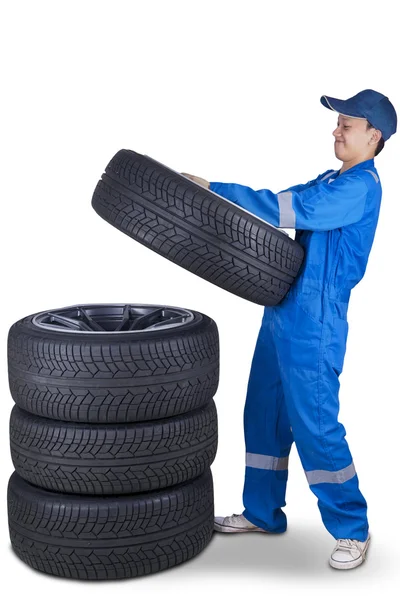 Jeune mécanicien empiler des pneus — Photo
