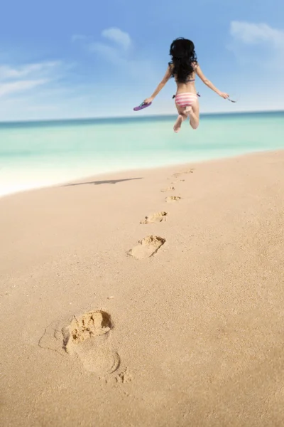 Pegadas na areia e mulher pulando — Fotografia de Stock